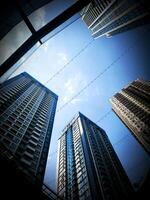 Photo of tall modern buildings standing against a bright blue sky, ideal for urban landscape, city architecture, business district, and travel related themes