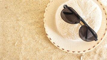 Top view flat lay of summer hat and sunglasses isolated on beach sand background photo