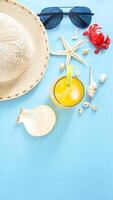 Flat lay arranged of summer concept with a glass of cold refreshing summer drink, sunglasses, summer hat, sea shells, starfish, and crab miniature isolated on blue background photo