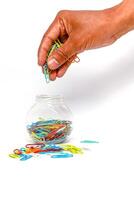 Hand placing colorful paper clips into a jar, symbolizing organization and office supplies for a creative workspace photo