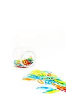 Vibrant Multicolored Paper Clips Spill from Clear Container on White Background photo