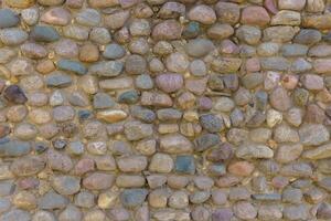 Wall fence of stones of different sizes roughly stacked on top of each other and fastened with cement. Industrial background. photo