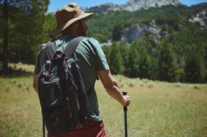Man Hiking in Mountain Landscape with Backpack and Trekking Poles photo