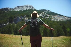 Man Hiking in Rugged Mountain Terrain on a Sunny Day photo
