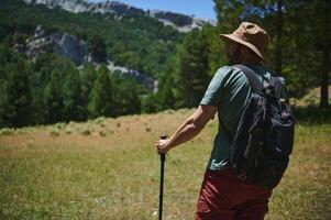 Man Hiking in the Mountains, Exploring Nature with Backpack and Hat photo