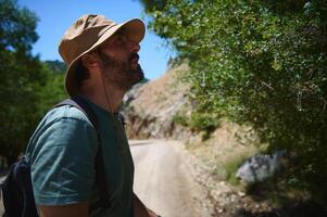 Bearded Man Hiking in Sunny Mountainous Terrain, Exploring Nature and Adventure photo