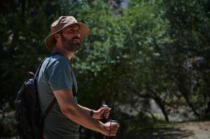 Man Hiking in the Mountains on a Summer Day with Backpack and Hat photo