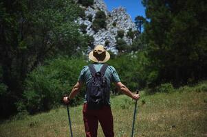 Adventurous Man Hiking Through Scenic Mountain Landscape on a Sunny Day photo
