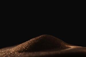 Gold sparkly hourglass sand on black background. Minimalist low key poto for concepts of time, travel to the desert photo