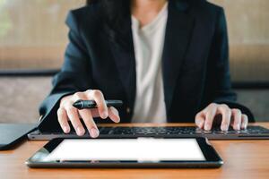 A business professional multitasking with a tablet and laptop, showcasing modern technology in a work environment. photo