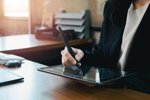 Businesswoman using a digital tablet with a stylus in a modern office environment, emphasizing technology and productivity. photo