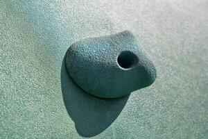 An artificial blue climbing hold on a wall. Close up photo