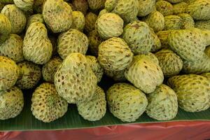 custard apple piled up on banana leaves photo