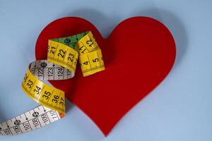 A red heart shape with measuring tape symbolizing health care photo