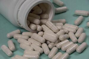 One bottle of pills, some of which spilled into a light blue surface photo