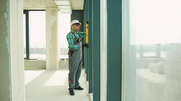 Construction worker checking vertical alignment of window frame with spirit level video