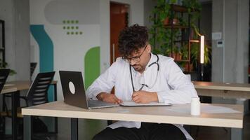 Doctor writing notes while working on laptop in modern clinic video