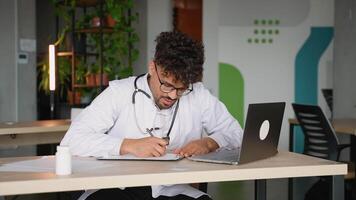 Doctor writing notes on paper at his desk video