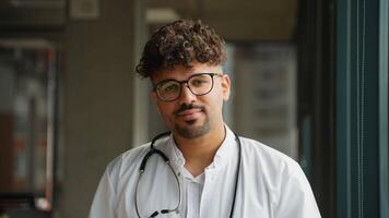 Young doctor smiling and looking at camera in hospital corridor video