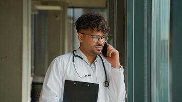 Doctor discussing a medical case on the phone near window video
