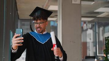 Happy graduate making a call showing his diploma video