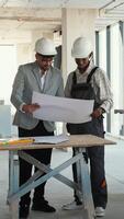 Architect and construction worker discussing blueprint on construction site video