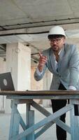 Architect using laptop and reviewing blueprints on construction site video