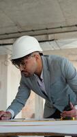 Architect reviewing blueprints and talking on walkie talkie video