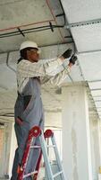 Electrician installing cables on a ladder in building under construction video