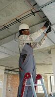 Electrician installing cables on a ladder in building under construction video