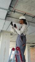 Electrician installing cables on a ceiling using a ladder video