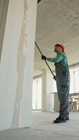 Construction worker priming walls in new building video
