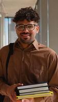 Smiling student holding books in a modern hallway setting video