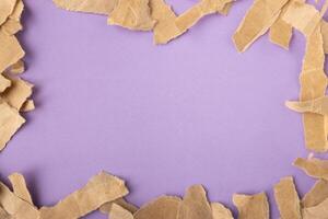 Brown torn craft paper strips frame on purple surface background photo