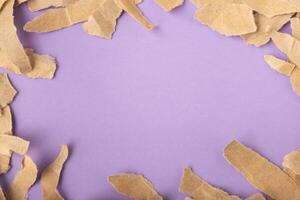 Torn kraft paper frame on purple surface background photo