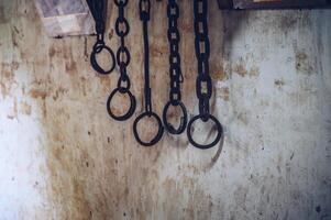Group of rusty metal shackles or handcuff hanging on the wall. A shackle is a restraint, either physical or psychological, that restricts movement. photo