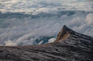 Mountain peak above fluffy clouds photo
