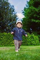 A joyful toddler is happily exploring the wonders of nature in a bright, sunny outdoor setting filled with greenery and playful vibes, showcasing the essence of childhood and carefree adventure photo