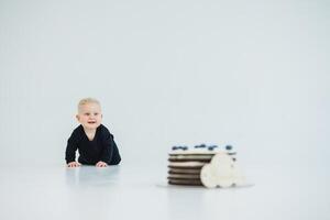 An adorable and cute baby is crawling eagerly towards a delicious birthday cake placed beautifully on a minimalist white background, creating a joyful scene perfect for capturing a delightful moment photo