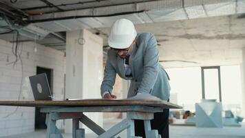 Architect reviewing blueprints on construction site and having a call video