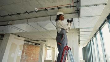 Electrician installing cables on a ceiling in a building under construction video