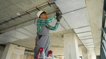 Electrician installing electrical wiring on ceiling video