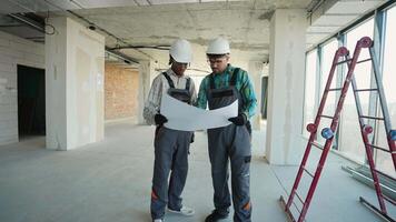 Construction workers examining blueprint in unfinished building video