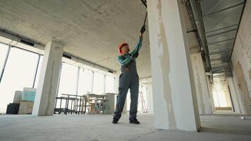 Construction worker painting walls and pillars in a building under construction video