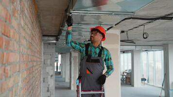 Electrician installing cable tray on ceiling in building under construction video