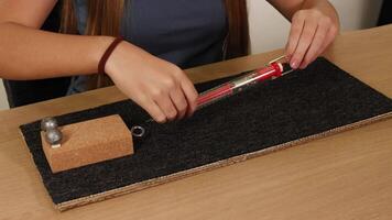 Hands use a spring scale to measure frictional force on a block across a carpeted surface video