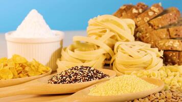 A variety of grains, pasta, and bread arranged against a bright blue backdrop, highlighting textures and colors video