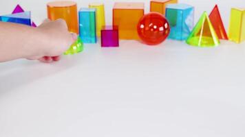 Vibrant 3D geometric shapes interact on a white surface, highlighting movement and color contrast in a playful educational setting video