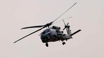 A Sikorsky MH-60R helicopter flies smoothly in overcast skies, showcasing its military design and capabilities at the Avalon Airshow video