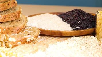 A variety of grains and sliced bread are artfully arranged on a wooden surface under bright lighting, showcasing texture and color video